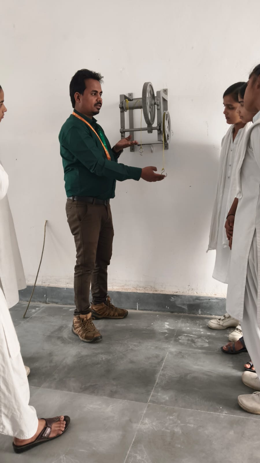 Faculty demonstrating worm and worm wheel apparatus in physics lab